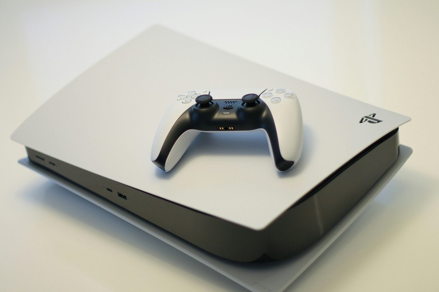 A PlayStation 5 console with a DualSense controller placed on top of it.